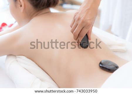beautiful and healthy young woman  during a back stone therapy massage in spa salon
