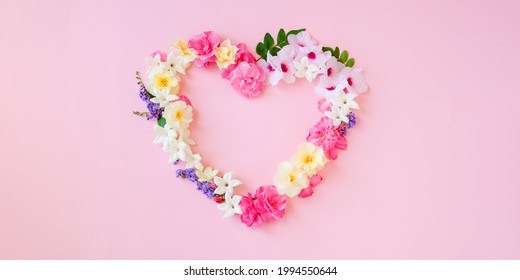 Beautiful heart shaped,Frame composition,various fresh flowers on pink background.Copy space.Valentines, mothers,women's day concept.Flat lay,top view.Template,design of wedding invitations,cards.