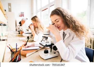 Beautiful high school students with microscopes in laboratory. - Powered by Shutterstock