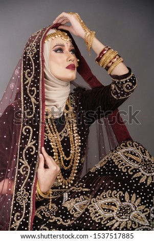 Beautiful hijab girl wearing traditional India costume lehenga choli or saree with kundan jewelry set isolated over grey background. Happy Deepavali celebration and Bollywood concept.
