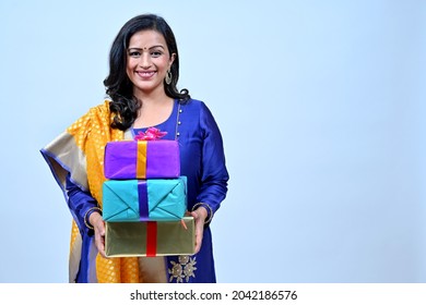 Beautiful hindu women in Tradional wear holding gift boxes in hand in greeting pose, studio shot - Shutterstock ID 2042186576