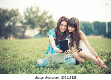 beautiful hipster young women sisters friends using tablet and smartphone in the park - Powered by Shutterstock