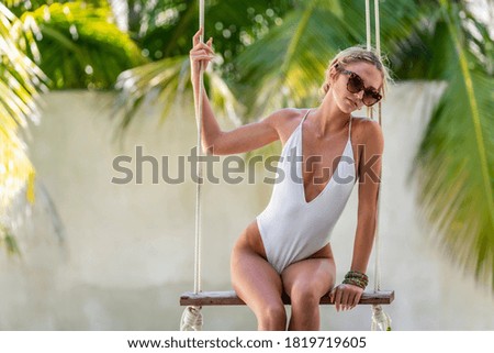 A beautiful hispanic bikini model swings by the pool in the Yucatán Peninsula near Merida, Mexico