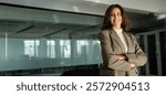 Beautiful hispanic business woman with crossed arms in suit smiling. European or latin confident good looking middle age leader female saleswoman businesswoman standing in office. Banner, copy space.