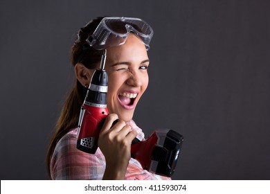 Beautiful Hispanic Carpenter Woman Holding A Power Drill, Gray Background