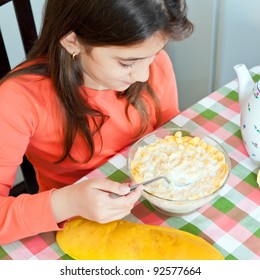 Beautiful Hispanic Girl Eating Breakfast On A Bowl With Milk And Cereal