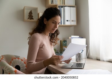 Beautiful Hispanic Millennial Woman Sit At Workplace Desk Reading Received Correspondence Letter, Learn Agreement Details, Get Commercial Offer Invitation, Do Paperwork From Home. Work Process Concept