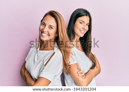 Beautiful hispanic mother and daughter smiling happy over isolated pink background.