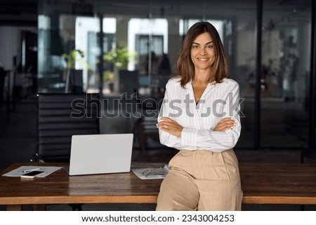Photo of Beautiful hispanic senior business woman with crossed arms smiling at camera. European or latin confident mature good looking middle age leader female businesswoman on office background, copy space.