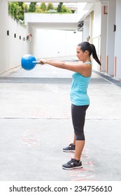 Beautiful Hispanic Sport Woman Swing The Blue Kettlebell, Outdoor