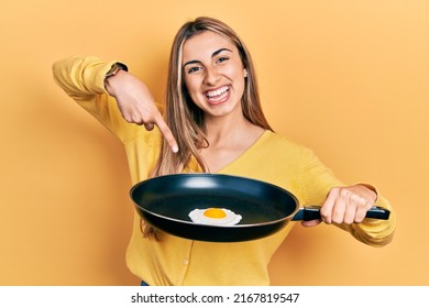 Beautiful Hispanic Woman Cooking Fried Egg Smiling Happy Pointing With Hand And Finger 