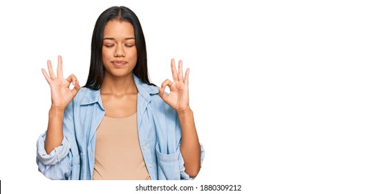 Beautiful Hispanic Woman Expecting A Baby Showing Pregnant Belly Relax And Smiling With Eyes Closed Doing Meditation Gesture With Fingers. Yoga Concept. 