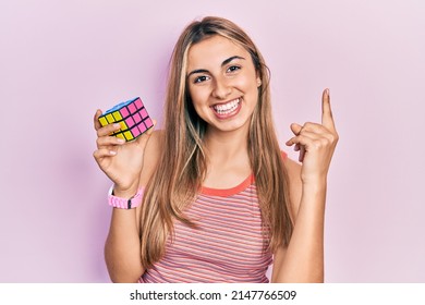 Beautiful Hispanic Woman Holding Colorful Puzzle Cube Intelligence Game Smiling Happy Pointing With Hand And Finger To The Side 