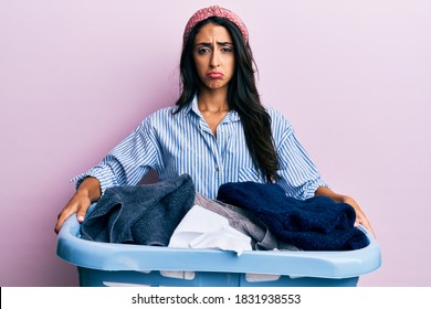 Beautiful Hispanic Woman Holding Laundry Basket Depressed And Worry For Distress, Crying Angry And Afraid. Sad Expression. 