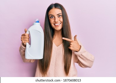 Beautiful Hispanic Woman Holding Laundry Detergent Bottle Smiling Happy Pointing With Hand And Finger 