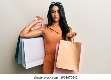 Beautiful Hispanic Woman Holding Shopping Bags Skeptic And Nervous, Frowning Upset Because Of Problem. Negative Person. 