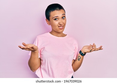 Beautiful Hispanic Woman With Short Hair Wearing Casual Pink T Shirt Clueless And Confused With Open Arms, No Idea Concept. 