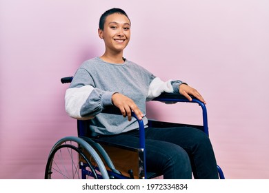 Beautiful hispanic woman with short hair sitting on wheelchair with a happy and cool smile on face. lucky person. 