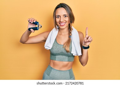 Beautiful hispanic woman training muscle with hand grip smiling with an idea or question pointing finger with happy face, number one 