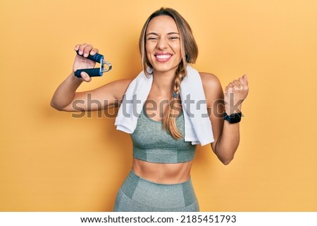 Beautiful hispanic woman training muscle with hand grip screaming proud, celebrating victory and success very excited with raised arm 