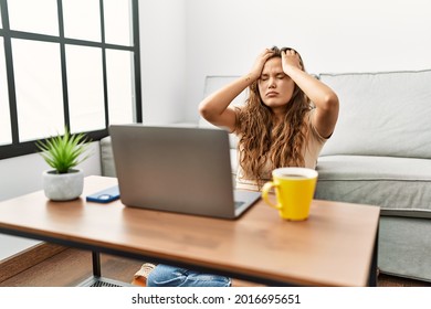 Beautiful Hispanic Woman Using Computer Laptop At Home Suffering From Headache Desperate And Stressed Because Pain And Migraine. Hands On Head. 