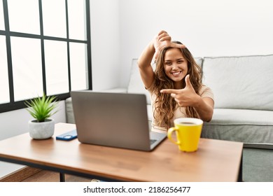 Beautiful Hispanic Woman Using Computer Laptop At Home Smiling Making Frame With Hands And Fingers With Happy Face. Creativity And Photography Concept. 