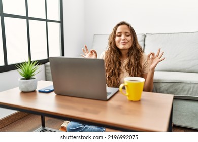 Beautiful Hispanic Woman Using Computer Laptop At Home Relax And Smiling With Eyes Closed Doing Meditation Gesture With Fingers. Yoga Concept. 