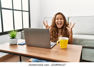 Beautiful Hispanic Woman Using Computer Laptop At Home Celebrating Victory With Happy Smile And Winner Expression With Raised Hands 