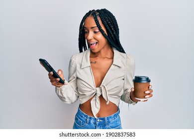 Beautiful Hispanic Woman Using Smartphone And Drinking A Cup Of Coffee Celebrating Crazy And Amazed For Success With Open Eyes Screaming Excited. 