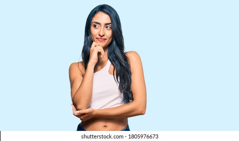 Beautiful Hispanic Woman Wearing Casual Clothes With Hand On Chin Thinking About Question, Pensive Expression. Smiling And Thoughtful Face. Doubt Concept. 