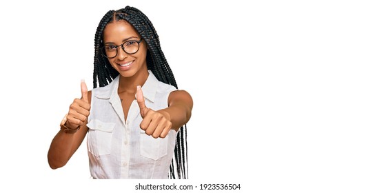 Beautiful hispanic woman wearing casual clothes and glasses approving doing positive gesture with hand, thumbs up smiling and happy for success. winner gesture. 