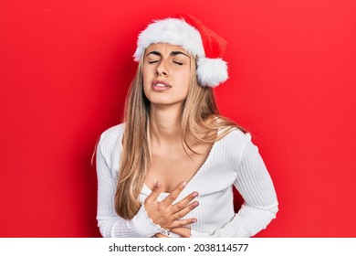 Beautiful Hispanic Woman Wearing Christmas Hat With Hand On Stomach Because Indigestion, Painful Illness Feeling Unwell. Ache Concept. 