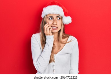 Beautiful hispanic woman wearing christmas hat looking stressed and nervous with hands on mouth biting nails. anxiety problem. 