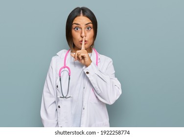 Beautiful hispanic woman wearing doctor uniform and stethoscope asking to be quiet with finger on lips. silence and secret concept. 