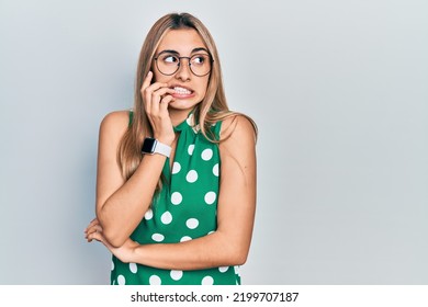 Beautiful hispanic woman wearing elegant shirt and glasses looking stressed and nervous with hands on mouth biting nails. anxiety problem.  - Shutterstock ID 2199707187
