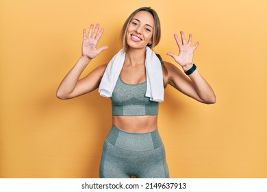 Beautiful hispanic woman wearing sportswear and towel showing and pointing up with fingers number ten while smiling confident and happy. 