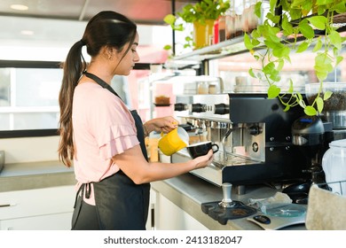 Beautiful hispanic woman working as a barista at the coffee shop while making a hot drink for a customer  - Powered by Shutterstock