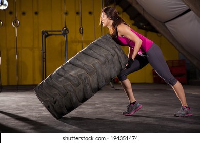 Beautiful Hispanic young woman halfway from flipping a tire in a cross-training gym - Powered by Shutterstock