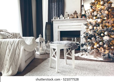 Beautiful Holiday Decorated Room With Christmas Tree, Fireplace And Armchair With Blanket. Cozy Winter Scene. White Interior With Lights.