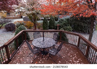 Beautiful Home Backyard Deck Covered In A Light Dusting Of Snow During Autumn With A Table And Chairs And Colorful Trees