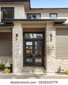 Beautiful Home Exterior On Sunny Day With Blue Sky. Features Front Door With Glass Panels And Columns Flanking Entrance.