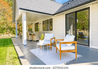 beautiful home exterior and patio on a bright colorful summer day with white painted house green grass lush landscape wicker deck furniture armchairs and blue sky - Powered by Shutterstock