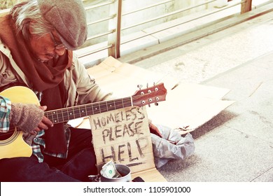 Beautiful Homeless man playing guitar on walking street in the capoital city.