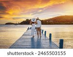 A beautiful honemyoon couple on a pier enjoys the tropical sunset in the Caribbean Sea, Antigua and Barbuda island