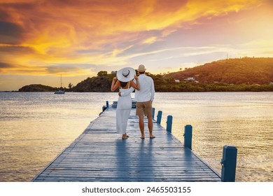 A beautiful honemyoon couple on a pier enjoys the tropical sunset in the Caribbean Sea, Antigua and Barbuda island - Powered by Shutterstock