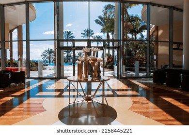 Beautiful hotel spa lobby with large windows overlooking the ocean, palm trees, pool and blue sky.Summer holidays on the amazing island of Madeira, Funchal - Powered by Shutterstock