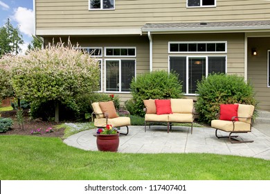 Beautiful house with backyard sitting area with sofas and chairs.