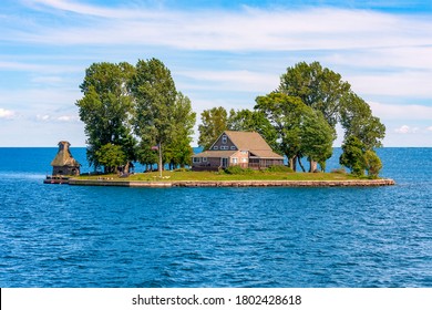 A Beautiful House And A Couple Of Large Trees Fit On A Small Island In The Middle Of A Large Lake