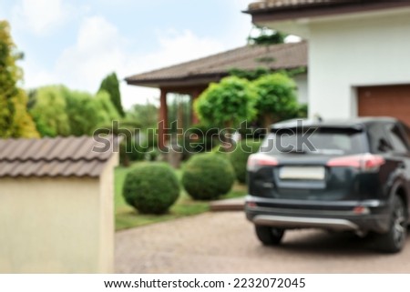 Beautiful house, green garden and parked car, blurred view