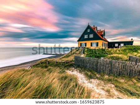 Beautiful House in typical yellow color on the beach with sea view during colorful sunset. Skagen coastline in North Jutland in Denmark, Skagerrak, North Sea